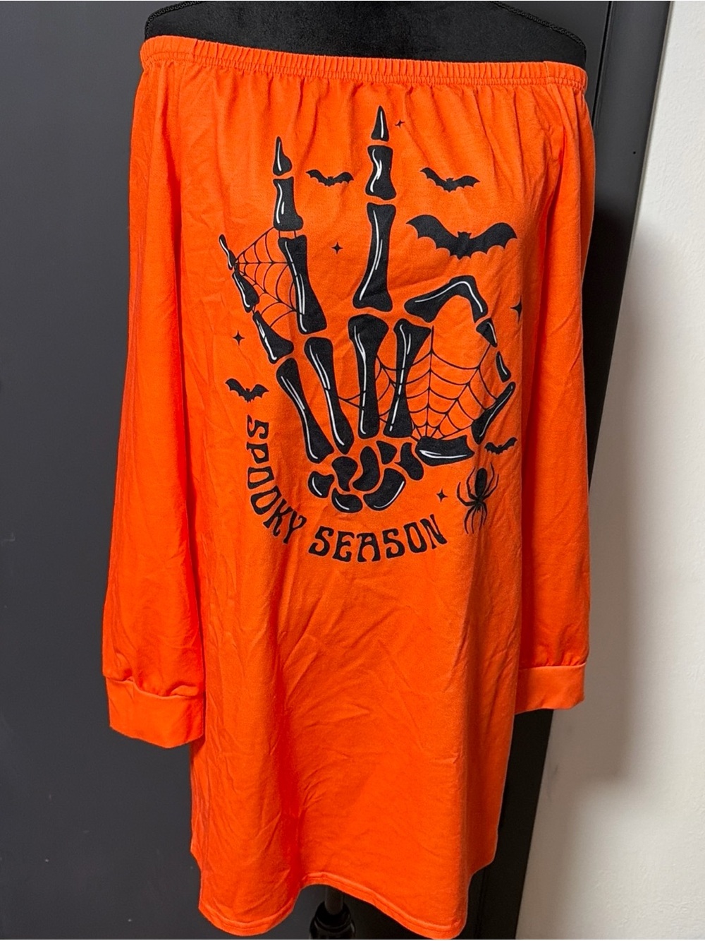 vibrant orange long-sleeve dress features a striking black skeleton hand graphic